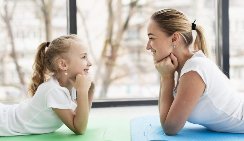 vue-laterale-de-la-mere-et-la-fille-posant-a-la-maison-sur-un-tapis-de-yoga vue-laterale-de-la-mere-et-la-fille-posant-a-la-maison-sur-un-tapis-de-yoga